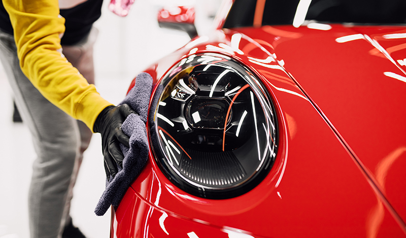 A man cleaning car with cloth, car detailing (or valeting) concept. Selective focus.